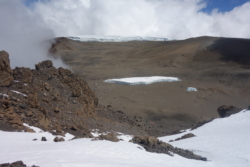»Als wir um kurz nach acht den Kraterrand bei Stella Point erreicht hatten, war mein Kopfweh verflogen. Unter uns, umbrabraun schweigend und ernst, absolut ernst, lag eine Hügellandschaft aus Asche, feierlich von einem Felsenkranz umzackt, dessen Innenseite mit Schnee geschmückt war. Weiß und strahlend auch die Gletscher am Kraterboden, mit ihren geriffelten Kanten hart von der Aschewüste abgegrenzt. Ja! dachte ich nur immer wieder, ja! Deshalb war ich gekommen.« (S. 7)
