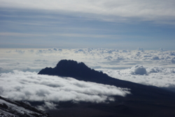 »Hinter ihnen sah man die wild gezackte Silhouette des Mawenzi, sie ragte als schwarzer Schattenriß über die Wolkendecke, die sich zum Teil schon um ihn herumgeschoben hatte und langsam auf den Kibo zutrieb. Eine unendliche Wolkendecke und ohne die kleinste Lücke, strahlend weiß bis zum Horizont. Darüber ein zartblauer Himmel, von feinen Wolkenbändern durchwebt. Der gefalle ihm nicht, meinte Hamza und setzte sich auf den Felsen neben mir.« (S. 31)