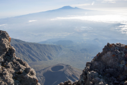 »Ich hatte schon einige Vulkane bestiegen, die mir mit ihrer Symmetrie imponiert hatten, insbesondere der Fudschi, er durfte fast als Kunstwerk gelten. In dieser Hinsicht konnte der Kilimandscharo nicht mithalten, er war gedrückter, rätselhafter, launischer als sie alle, die sich so makellos zu inszenieren wußten. Von ferne betrachtet, erschien er wie die plattgedrückte Kuppe einer aus Südost allzulange allzu flach ansteigenden Rampe – man unterschätzte ihn. Je höher man dann stieg, desto härter und dunkler wurde er.« (S. 60f.)