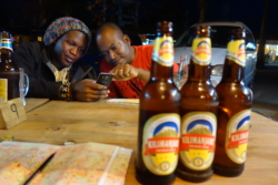 »Solomon schwärmte von den nächtelangen Gesprächen, die er mit seinen Mitbewohnern geführt habe. Noch heute schaffe er fünfzehn Flaschen Bier oder wahlweise eine Flasche Bier und dazu eine Flasche Konyagi, ›weißt du?‹ Er bot tatsächlich eine Wette an. Nicht mal der Tscharli wollte einschlagen. King Charles nützte die Gelegenheit, den Tscharli zu ermahnen, sich ja nicht wieder so sinnlos zu besaufen wie gestern. Der Tscharli versprach’s. Er sei zwar ein Quartalssäufer, ein Säufer sei er jedoch nicht!« (S. 79)